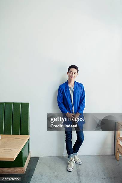 young man standing by wall - leaning stock pictures, royalty-free photos & images