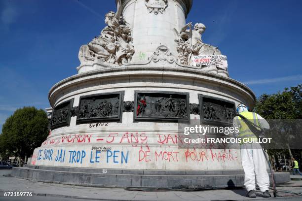 Man cleans the writing reading "Macron or Le Pen: 5 years in the street" on the statue on the place de la Republique in Paris on April 24 one day...
