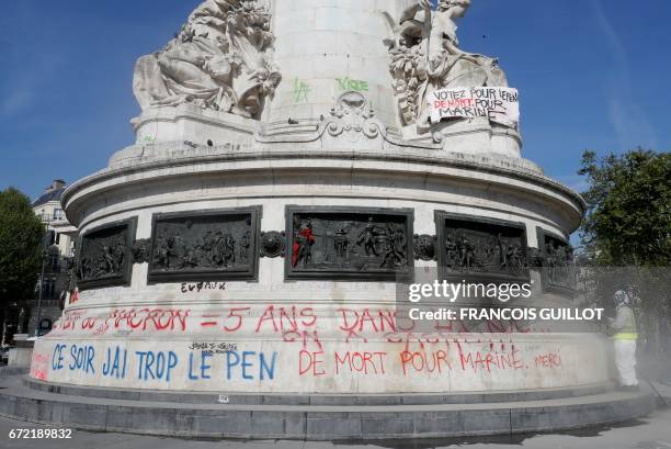 Man cleans the writing reading "Macron or Le Pen: 5 years in the street" on the statue on the place de la Republique in Paris on April 24 one day...