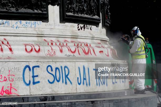 Man cleans the writing reading "Tonight I am in pain" on the statue on the place de la Republique in Paris on April 24 one day after moderate...