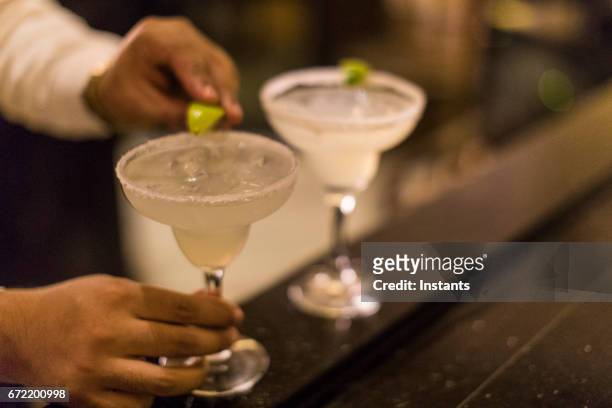 nahaufnahme einer unkenntlich panamaischen barkeeper, den letzten schliff auf eine margarita cocktail indem ein limettenschnitz auf den glasrand. - barman tequila stock-fotos und bilder