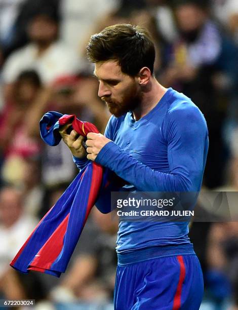 Barcelona's Argentinian forward Lionel Messi looks at his jersey after brandishing it to celebrate his goal during the Spanish league Clasico...