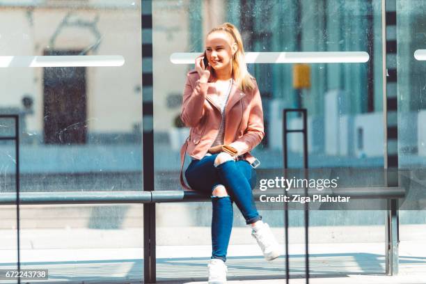 学生のバス待合い所で携帯電話を使用して - bus shelter ストックフォトと画像