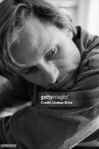 Extreme close-up view of Viggo Mortensen in a cotton button-down shirt as his chin rests upon his left shoulder and he looks downward to his left...