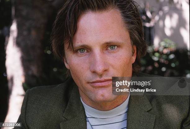 Close-up view of Viggo Mortensen wearing a green sport coat and light blue striped tee as he looks directly into the lens during a photo shoot on...