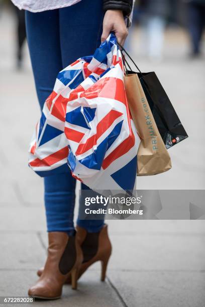 Shopper holds carrier bags featuring a Union flag, also known as the Union Jack, on Oxford Street in central London, U.K., on Monday, April 24, 2017....
