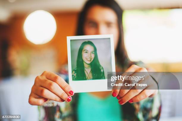 brunette teenager holding a polaroid picture - teen photography stock pictures, royalty-free photos & images