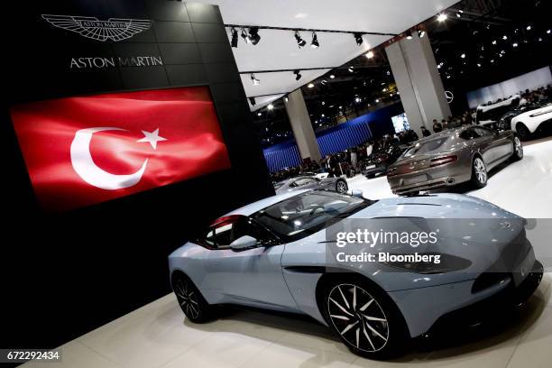 An Aston Martin DG11 luxury automobile, manufactured by Aston Martin Holdings UK Ltd., sits on display beneath a Turkish national flag at the...