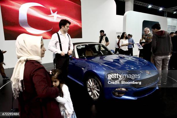 Visitors inspect a Fiat 124 Spider sportscar, manufactured in Turkey by Fiat Chrysler Automobiles NV, displayed beside a Turkish national flag...