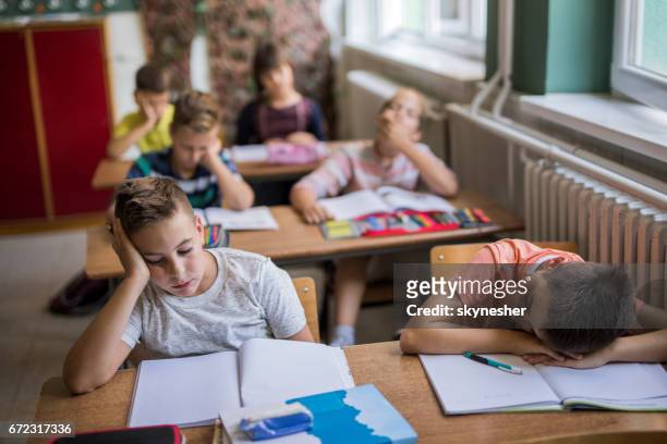 group of bored elementary students in the classroom. - bores stock pictures, royalty-free photos & images