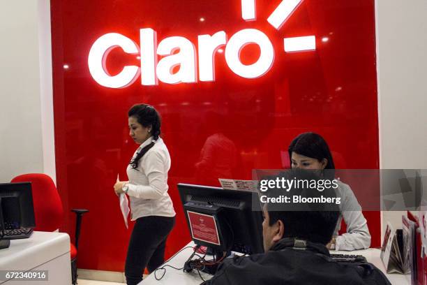Employees assist customers at an America Movil SAB Claro Colombia store in Bogotá, Colombia, on Saturday, April 8, 2017. America Movil SAB is...