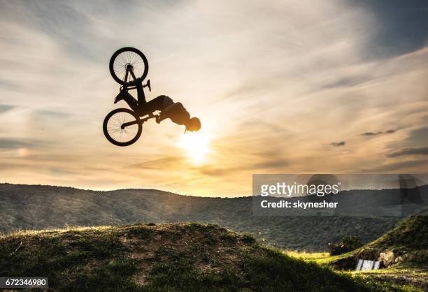 hombre en bicicleta haciendo backflip contra el cielo al atardecer. - backflipping fotografías e imágenes de stock