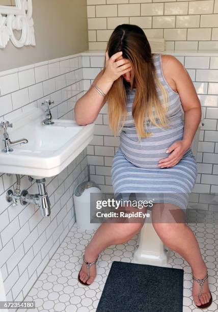 very pregnant and miserable woman sitting on toilet seat, crying - muscular contraction stock pictures, royalty-free photos & images