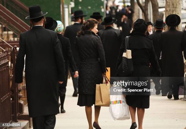 Hasidic men and women walk through a Jewish Orthodox neighborhood in Brooklyn on April 24, 2017 in New York City. According to a new report released...