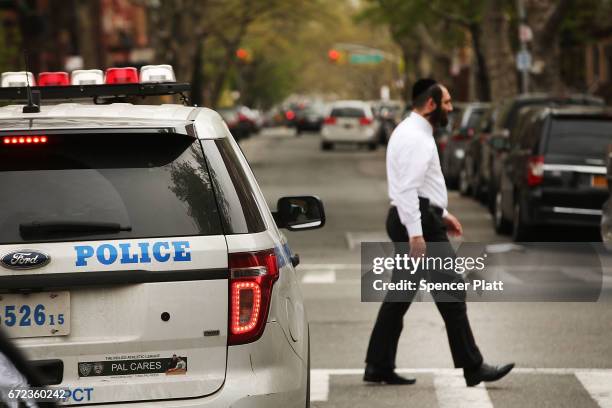 Hasidic man walks by a police car in a Jewish Orthodox neighborhood in Brooklyn on April 24, 2017 in New York City. According to a new report...