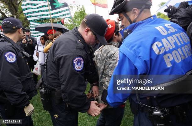 Capitol Police handcuff a pro-cannabis activist who lit up during a rally on Capitol Hill on April 24, 2017 in Washington, DC. / AFP PHOTO / MANDEL...