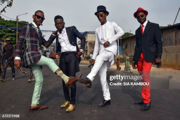 Members of La SAPE movement parade in a street of Abidjan on April 24, 2017 during a day of tribute to late Congolese rumba star Papa Wemba as part...