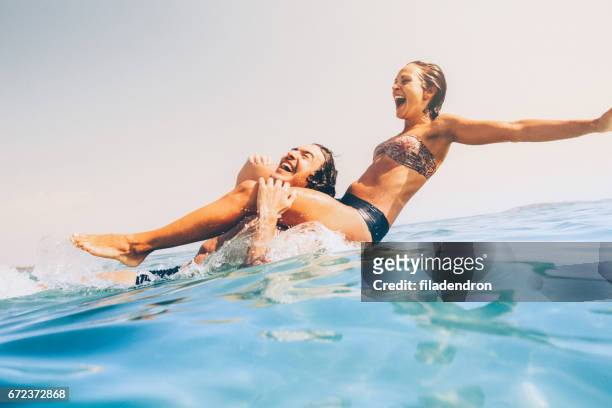 couple having fun in the sea - friends beach fun stock pictures, royalty-free photos & images