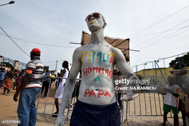 Man pose with body painting which translates as "Tribute to Papa" in a street of Abidjan on April 24, 2017 during a day of tribute to late Congolese...