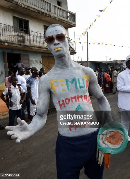 Man pose with body painting which translates as "Femua, Tribute to Papa" in a street of Abidjan on April 24, 2017 during a day of tribute to late...