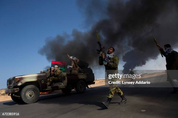 Opposition troops burn tires to use as cover during heavy fighting, shelling, and airstrikes near the main checkpoint near the refinery in Ras Lanuf...