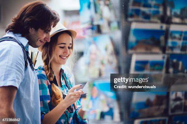 turismo joven comprar tarjetas postales de la tienda de souvenirs - tienda de regalos fotografías e imágenes de stock