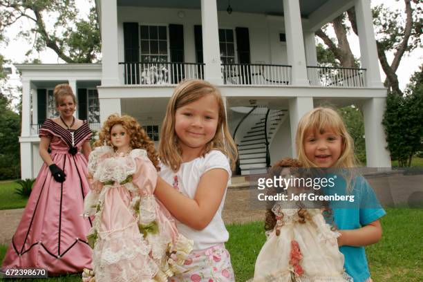 Two girls holding dolls outside the Oakleigh Historic Complex.