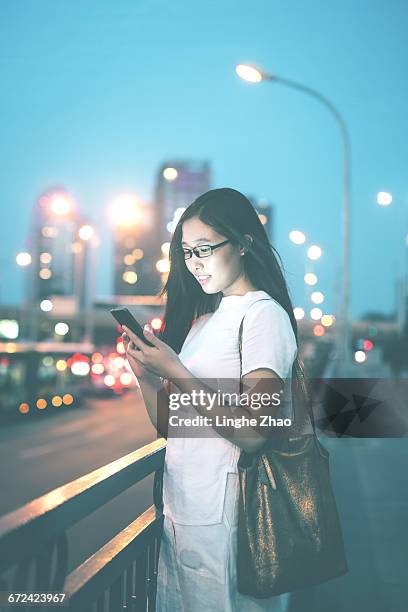 woman using mobile phone at night street - linghe zhao stock pictures, royalty-free photos & images