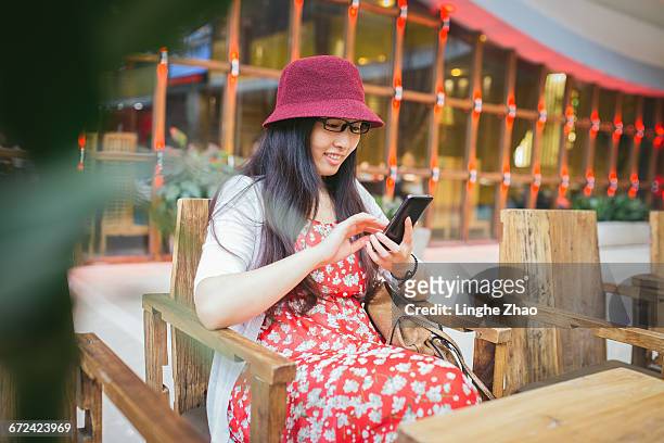 young woman using mobile phone - linghe zhao photos et images de collection
