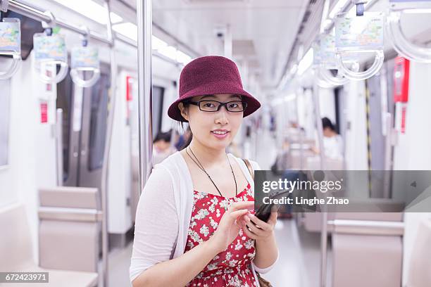 young asian woman with mobile phone in subway - linghe zhao stock pictures, royalty-free photos & images