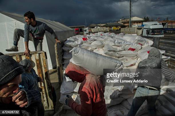 Turkish workers load bags of flour provided by the Turkish Red Crescent onto a truck bound for Syria, at the Turkish Syrian border, in Kilis, Turkey,...