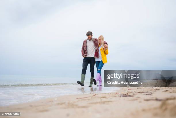 paar wandelen op het strand - laarzen geel stockfoto's en -beelden
