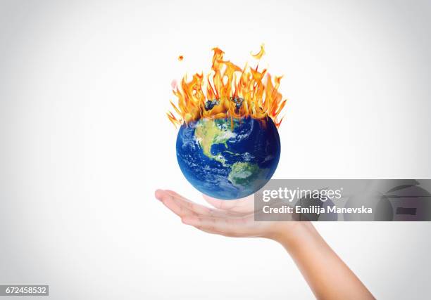 hands holding a globe on fire - global warming stock-fotos und bilder