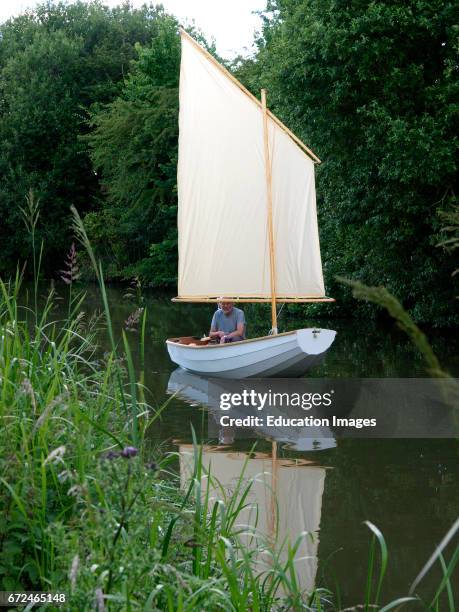 Man in a sail boat on the Kennet and Avon Canal, Devizes, Wilts, UK .