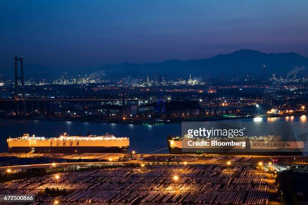 Hyundai Motor Co. Vehicles bound for export await shipment in front of a Eukor Car Carriers Inc. Roll-on/roll-off cargo ship, left, as a Wallenius...