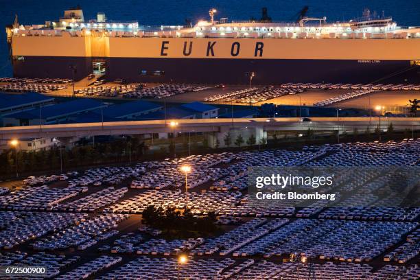 Hyundai Motor Co. Vehicles bound for export await shipment in front of a Eukor Car Carriers Inc. Roll-on/roll-off cargo ship at the company's Ulsan...