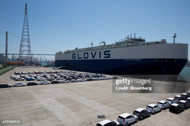 Hyundai Motor Co. Vehicles bound for export await shipment in front of a Hyundai Glovis Co. Roll-on/roll-off cargo ship at a port near the company's...