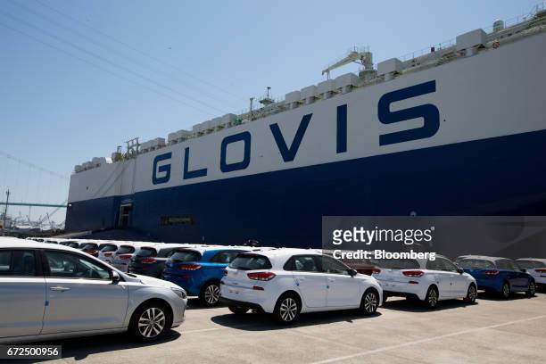 Hyundai Motor Co. Vehicles bound for export await shipment in front of a Hyundai Glovis Co. Roll-on/roll-off cargo ship at a port near the company's...