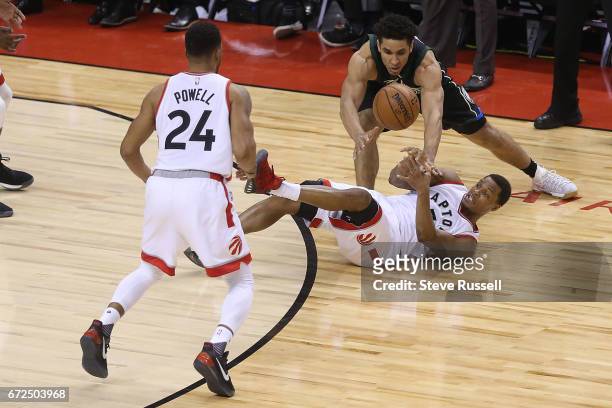 Falling Toronto Raptors guard Kyle Lowry makes a pass to Norman Powell as Milwaukee Bucks guard Malcolm Brogdon looks for the ball as the Toronto...