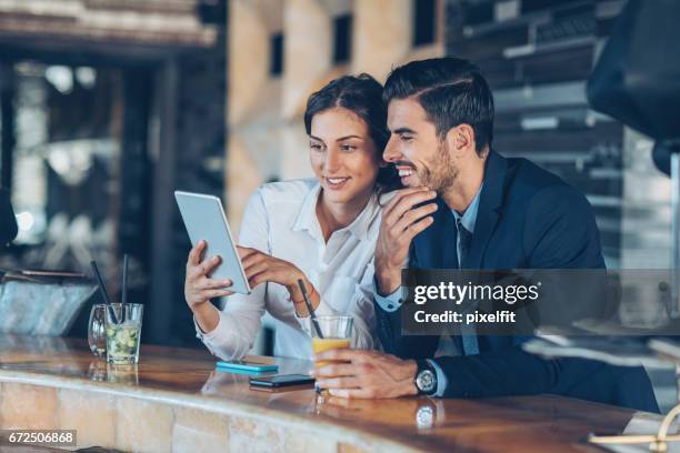 geschäftsleute mit digital-tablette und getränke in der lobby des hotels - business couple stock-fotos und bilder