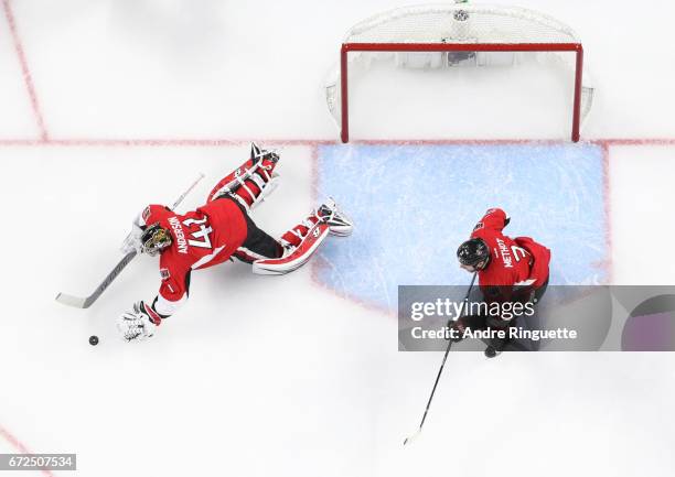 Craig Anderson of the Ottawa Senators dives to cover the puck against the Boston Bruins as Marc Methot looks on in Game Five of the Eastern...