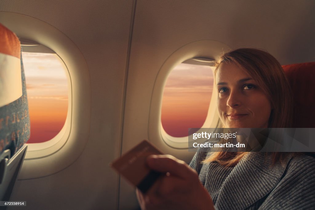 Young woman in airplane paying with credit card