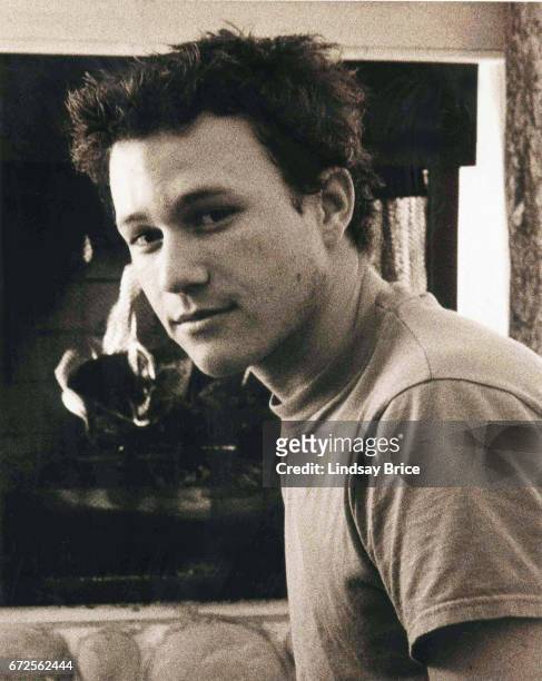 January 1999: View in sepia tone of Heath Ledger as he takes a break from festivities to rest on a hearth before a fireplace in a condominium during...