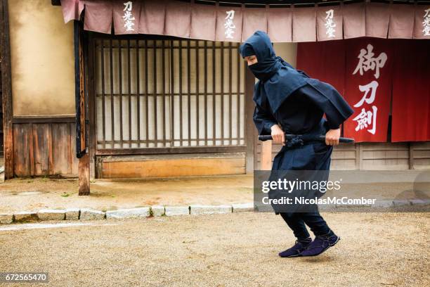 ninja giapponese in costume nero stalking nel villaggio di edo - ninja costume foto e immagini stock