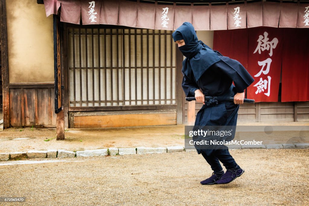 Japanese ninja in black costume stalking in Edo village