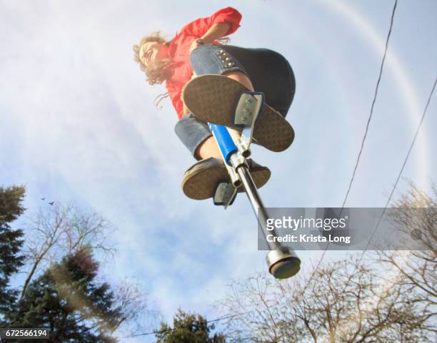 girl jumping on a pogo stick. - mens long jump stockfoto's en -beelden
