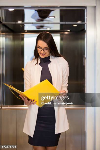 young business woman in elevator reading contrat - contrat stock pictures, royalty-free photos & images