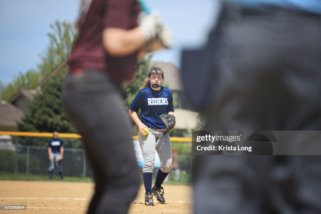 Teenage softball player throwing a pitch.