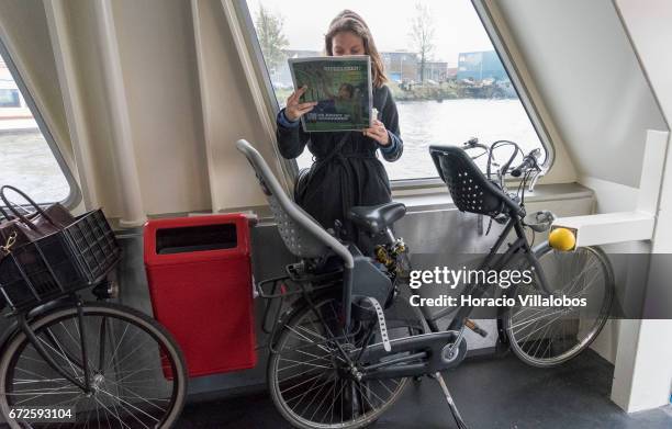 Passenger reads the newspaper onboard a ferry sailing to Central Station from NDSM on April 21, 2017 in Amsterdam, Netherlands. GVB ferries...