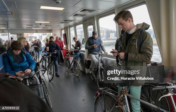 Passengers check their cellphones onboard a ferry sailing to Central Station from NDSM on April 21, 2017 in Amsterdam, Netherlands. GVB ferries...